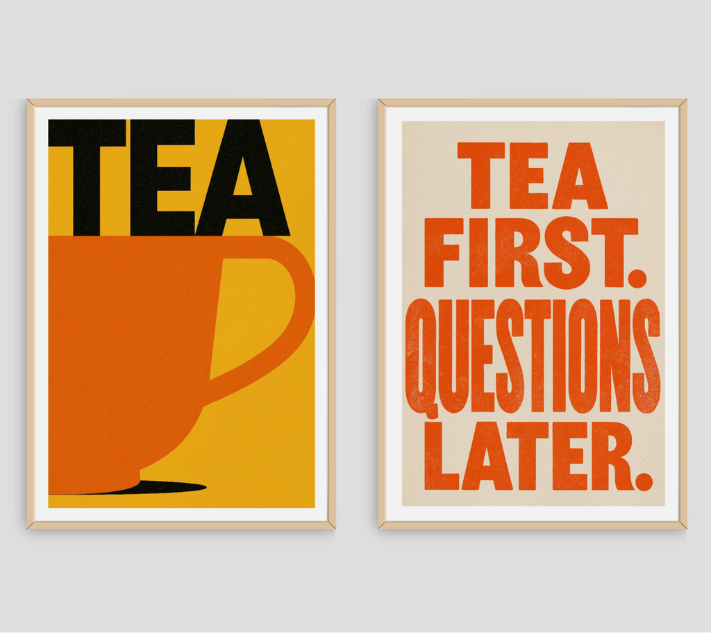 Two framed typographic wall art prints hanging side by side on a light gray wall. The left print has a mustard yellow background, black 'TEA' text, and an orange teacup.