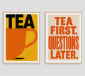 Two framed typographic wall art prints hanging side by side on a light gray wall. The left print has a mustard yellow background, black 'TEA' text, and an orange teacup.